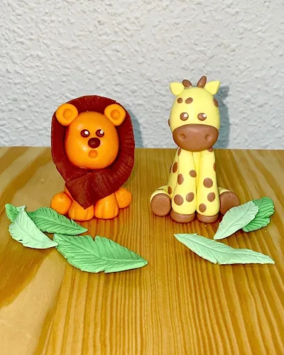 Figuras de fondant caseras hechas por la Pilareta y comestibles, son un león, una jirafa y hojitas de jungla.